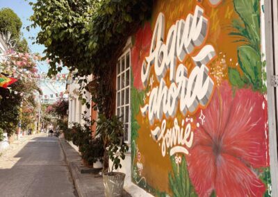 A colorful mural featuring hibiscus blossoms on the facade of a colonial-style house