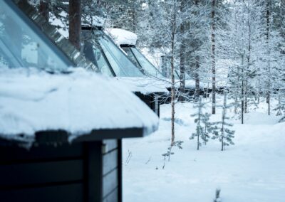 Glas-Iglu in Finnland: verschneite Glasdächer der Aurora Cabins zwischen den Kiefern