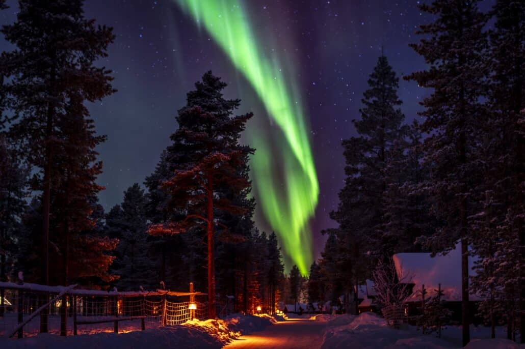 Northern Lights over the illuminated path through the resort near Ivalo