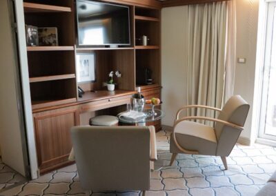 Wohnzimmer der Owner's Suite der MS Discoverer mit Sesseln, Schreibtisch und Tür zum Balkon