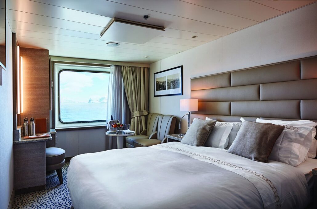 Deck 4 Superior Single Cabin on the MS Heritage Discoverer, featuring a bed, two armchairs, a desk, and a large window
