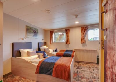 Zweibettkabine der MS Plancius mit zwei unteren Betten, Schrank und Fenster