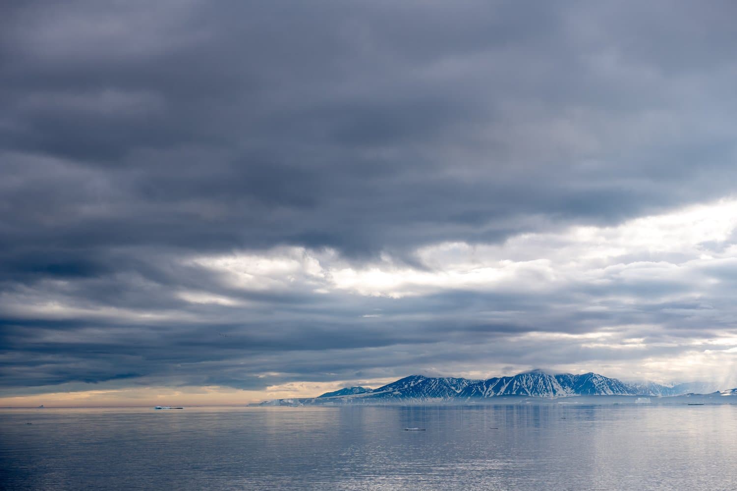 Blick vom Meer auf die Berge der grönländischen Küste unter Wolken View from the sea of the mountains along the Greenlandic coast beneath the clouds