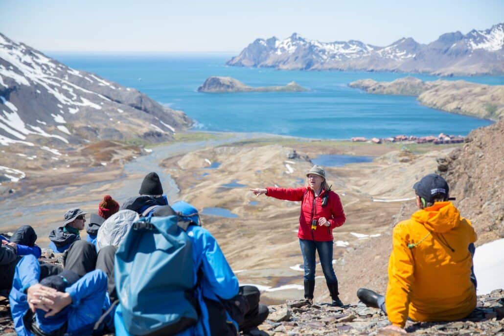 Wandergruppe mit Guide auf einer Anhöhe über einer Bucht Südgeorgiens