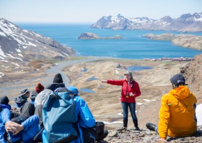 Wandergruppe mit Guide auf einer Anhöhe über einer Bucht Südgeorgiens