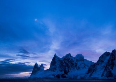 Rocky peaks of the Lemaire Channel during the blue hour, illuminated by the moon