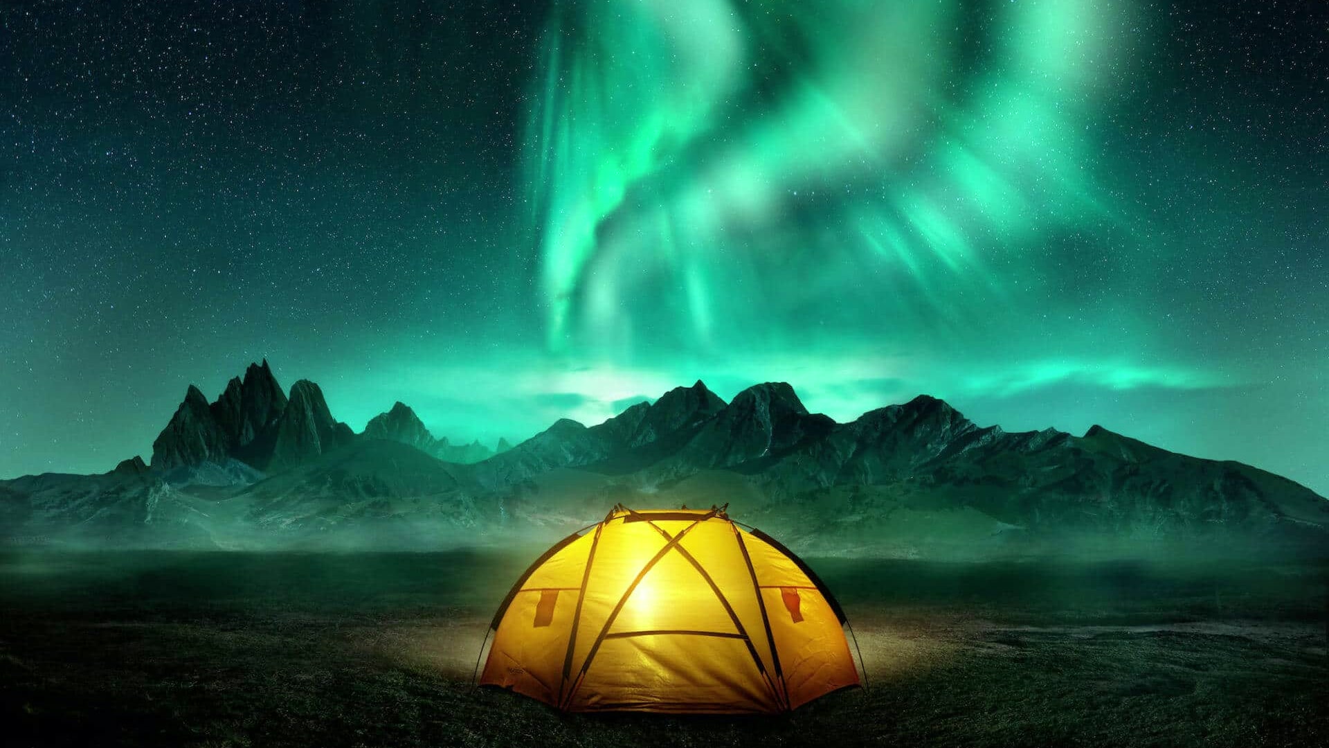 Ein gelbes Zelt leuchtet unter dem Polarlicht vor dunklen Bergen