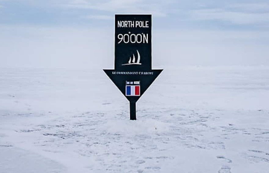 Wegweiser „North Pole 90°00'N“ im Schnee am geografischen Nordpol